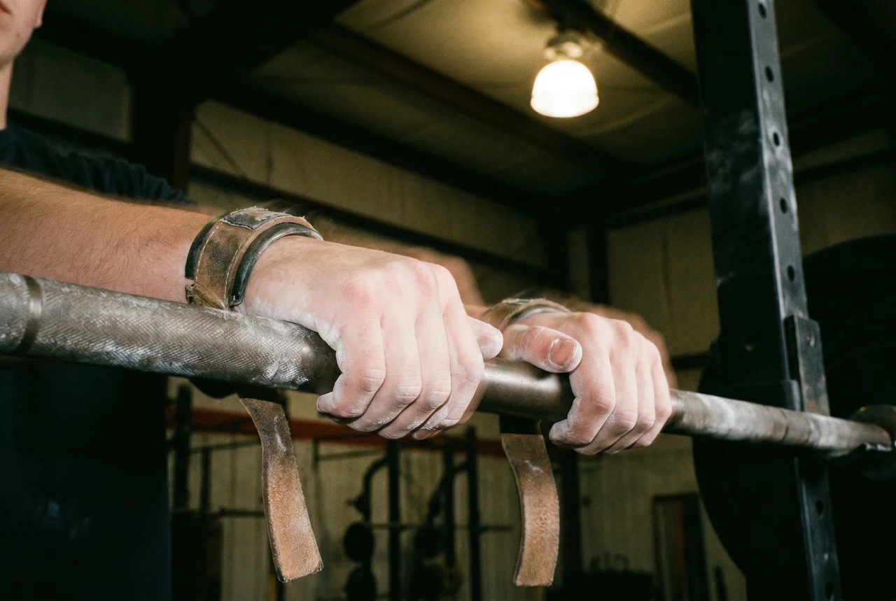 Young athlete hands gripping barbell with chalk